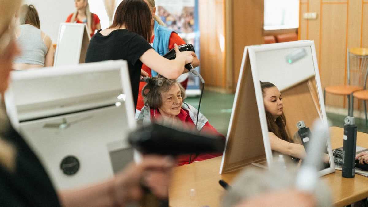 Senior woman smiling during a styling session at a vibrant hair salon in Karviná.