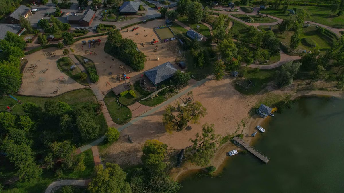 Aerial shot of a lakeside park with playground and shoreline during the day.